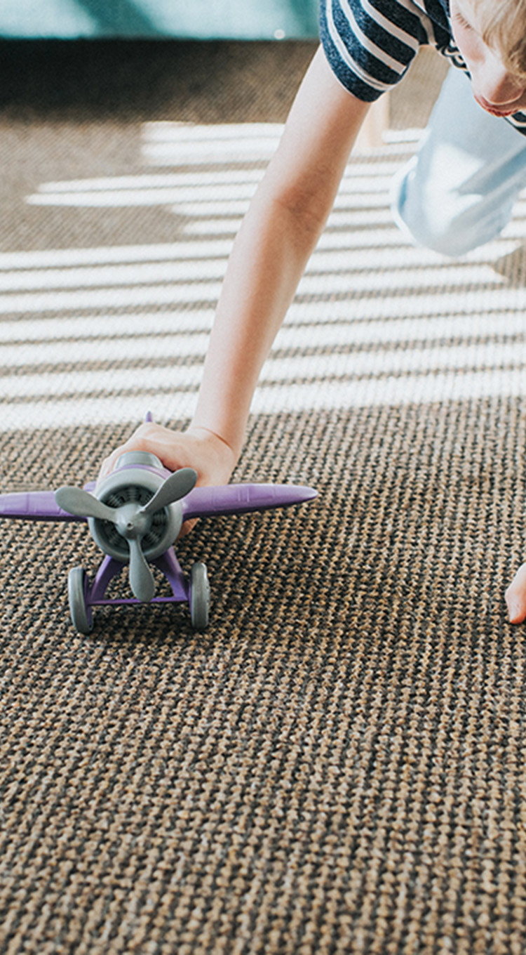Child playing with toy on durable carpet