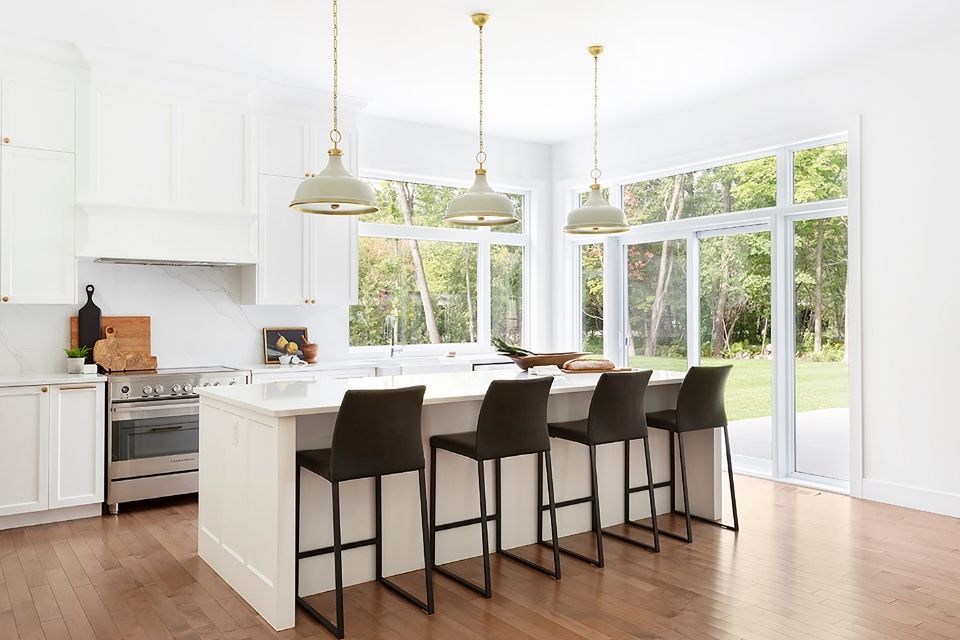 Bright white kitchen with black barstools in minimalist modern home by Hibou Design + Co.