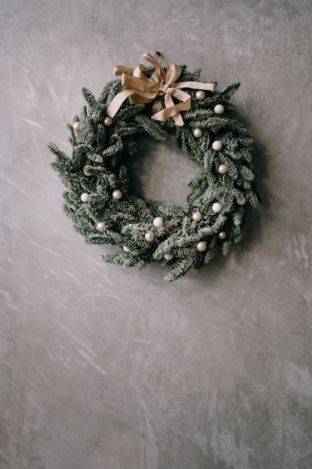 Green Christmas wreath with beige colored bow and ornaments