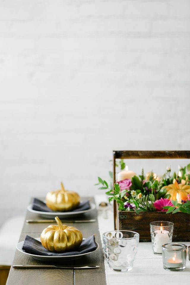 Holiday table styled with small gold pumpkins and fresh flowers