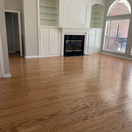 wood floors in empty living room, fire place, white walls